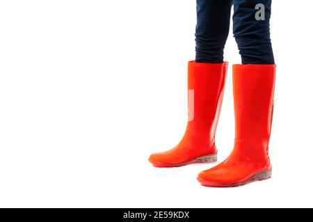 Gros plan des jambes des femmes dans des chaussures en caoutchouc rouge isolées sur fond blanc. Météo de la saison des pluies. Banque D'Images