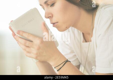 Les mains pliées dans la prière sur une Sainte Bible dans le concept d'église pour la foi, la spiritualité et la religion, la femme priant sur la sainte bible le matin. Banque D'Images