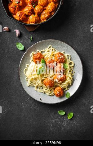 Pâtes spaghetti aux boulettes de viande, sauce tomate, fromage râpé et basilic frais - pâtes italiennes maison saines sur fond noir, vue du dessus, espace copie Banque D'Images
