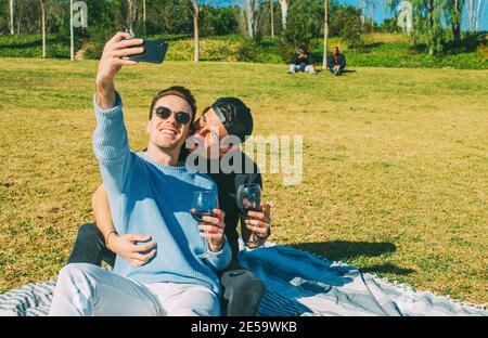 Jeune adulte caucasien gay couple prenant un Selfie avec Mobile Téléphone tout en buvant du vin rouge Banque D'Images