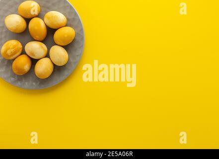 Oeufs peints en or de Pâques dans une assiette grise sur fond jaune, concept de fête de pâques Banque D'Images