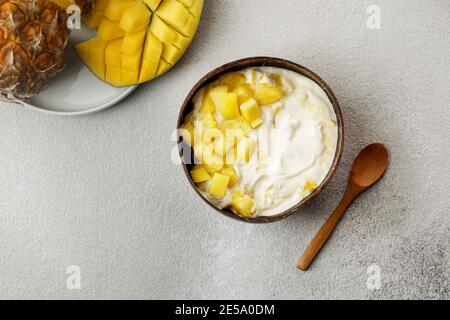 petit déjeuner sain, yaourt à la mangue et à l'ananas frais dans le bol à noix de coco Banque D'Images