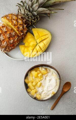 petit déjeuner sain, yaourt à la mangue et à l'ananas frais dans le bol à noix de coco Banque D'Images