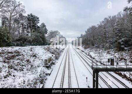 La ligne de chemin de fer entre Woking et Brookwood dans une coupe vue d'un pont au-dessus d'un jour de neige en hiver, Woking, Surrey, sud-est de l'Angleterre Banque D'Images