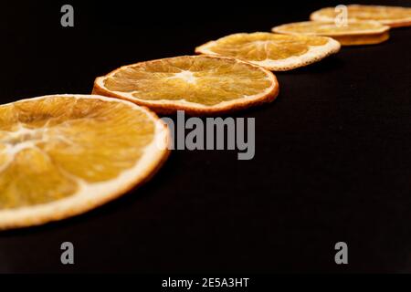 Gros plan sur des oranges séchées tranchées en diagonale sur fond noir. Banque D'Images