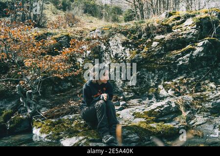 Portrait d'une jeune fille assise sur un rocher de mousse à côté d'une rivière dans la nature Banque D'Images