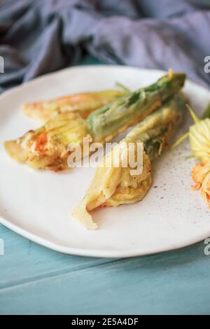 Courgette battue et frite ou fleurs de courge Zucchini filmées d'en haut sur une table rustique bleue avec un premier plan et un arrière-plan flous. Banque D'Images