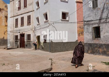 El Jadida, Maroc - 16 avril 2016: Scène de rue dans la ville d'El Jadida, avec une femme portant une robe traditionnelle dans une allée à l'ancien portugais Banque D'Images