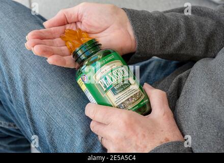 Gros plan des mains de la personne de l'homme tenant bouteille de supplément d'huile de lin de lin suppléments gélules capsules Banque D'Images
