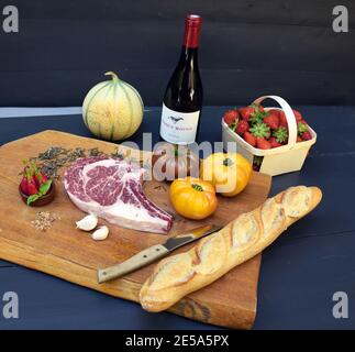 Viande Black Angus, tomates, baguette, fraises et vin rouge sur bois, France, Provence, Vaucluse, Pernes-les-Fontaines Banque D'Images