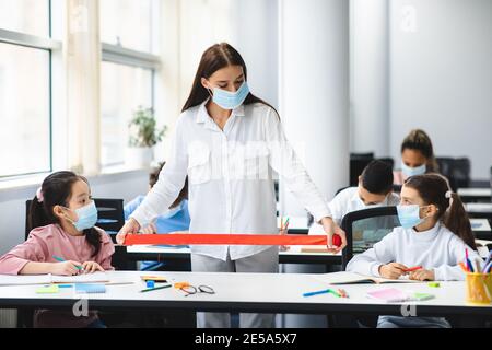 Professeur dans le masque facial en utilisant le ruban rouge mesurant la distance sociale Banque D'Images