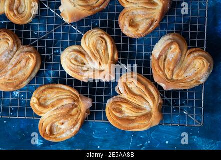 Petits pains à sucre faits maison sur une grille de refroidissement. Palmiers, oreilles d'éléphant, biscuit de pâte feuilletée. Banque D'Images