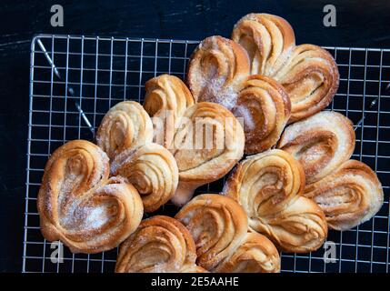 Petits pains à sucre faits maison sur une grille de refroidissement. Palmiers, oreilles d'éléphant, biscuit de pâte feuilletée. Banque D'Images