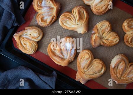 Petits pains à sucre faits maison sur une plaque de cuisson. Palmiers, oreilles d'éléphant, biscuit de pâte feuilletée. Banque D'Images