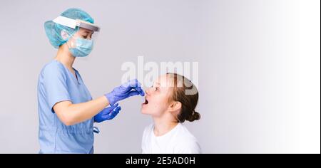 Bannière, format long. Un professionnel de la santé en vêtements de protection effectue une analyse pour un test COVID 19 à partir d'un écouvillon buccal. Fond gris et vide Banque D'Images