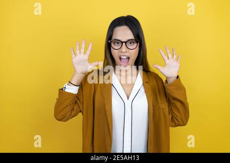 Jeune belle femme portant un blazer sur fond jaune isolé montrer et pointer vers le haut avec les doigts numéro dix tout en souriant confiant et hap Banque D'Images