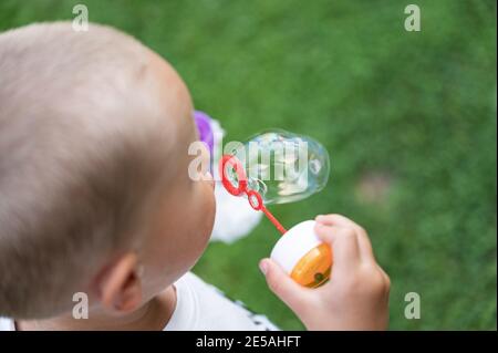 Vue en hauteur d'un enfant en bas âge qui soufflait de bulles de savon à l'extérieur. Banque D'Images