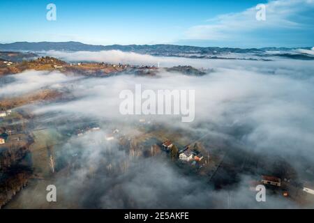 Vue aérienne du magnifique paysage brumeux dans la campagne bosniaque au lever du soleil. Image en tons. Zepce, village Ozimica. Banque D'Images