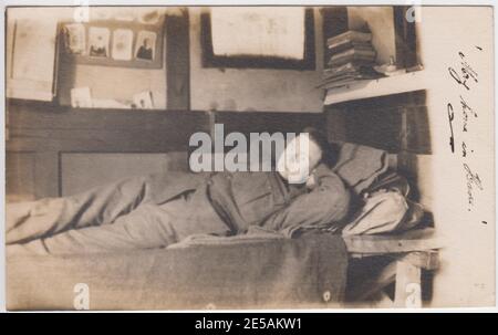 Soldat de la première Guerre mondiale couché sur son lit superposé. Des photos de famille et une pile de livres peuvent être vues en arrière-plan Banque D'Images