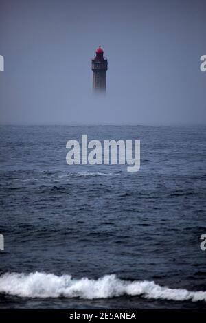 Le spectaculaire phare de la Jument, dans le brouillard estival, au large de l'Ile d'Ouessant, Bretagne. Le phare emblématique de 47 mètres de haut était bui Banque D'Images