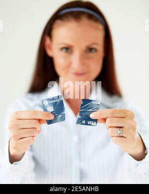 Femme tenant la carte de crédit coupée en deux Banque D'Images