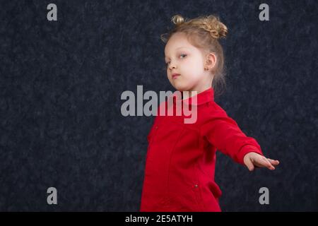 Belle petite fille dans une robe rouge étire sa main.