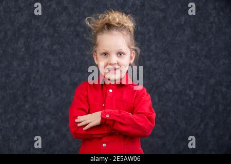 Belle petite fille blonde dans une robe rouge souriante. Enfant de cinq ans.