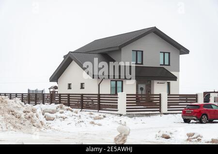 Krasnodar, Russie - janvier 23 2021: Maison privée de deux étages entourée d'une clôture et d'une voiture rouge Banque D'Images