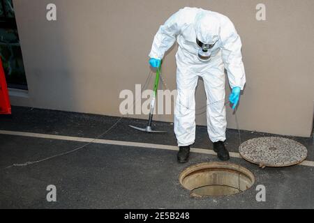 Marseille, France. 26 janvier 2021. Un travailleur de la santé portant un équipement individuel (EPI) inspectant un trou de ramassage. L'unité COMETE (Covid Marseille Environmental Testing expertise) recueille des échantillons d'eaux usées à divers endroits de la ville pour déterminer les quartiers, les écoles ou certains bâtiments contaminés par Covid-19 par des tests de ces échantillons. Crédit : SOPA Images Limited/Alamy Live News Banque D'Images