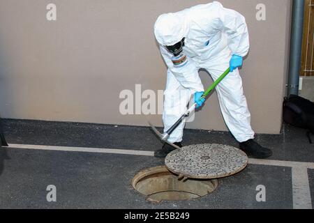 Marseille, France. 26 janvier 2021. Un professionnel de la santé portant une combinaison d'équipement de protection individuelle (EPI) prend le couvercle d'un trou d'homme pour inspection à Marseille. L'unité COMETE (Covid Marseille Environmental Testing expertise) recueille des échantillons d'eaux usées à divers endroits de la ville pour déterminer les quartiers, les écoles ou certains bâtiments contaminés par Covid-19 par des tests de ces échantillons. Crédit : SOPA Images Limited/Alamy Live News Banque D'Images