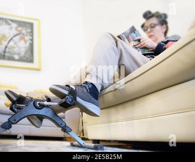 Une femme mûre fait de la pédalage, lit un livre et porte des rouleaux de cheveux. Banque D'Images