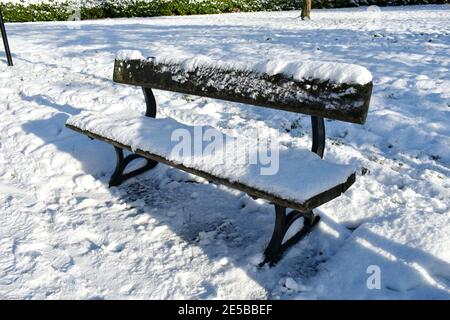 gros plan sur un banc de parc en bois vide recouvert de neige à la suite d'une chute de neige profonde. à l'extérieur, par temps ensoleillé et froid Banque D'Images