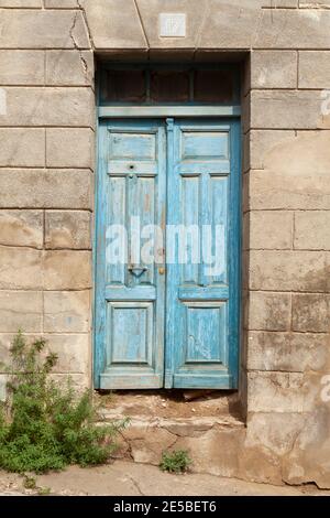 Une vieille porte en bois, fragile et décolorée, peinte en bleu, dans une rue perdue à la périphérie de la ville de Huesca, Aragon, Espagne. Banque D'Images