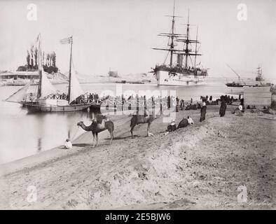 Photographie vintage du 19th siècle : navire dans le canal de Suez, Égypte. Quai de ferry et bateau pour traverser le canal, chameaux en premier plan. Banque D'Images