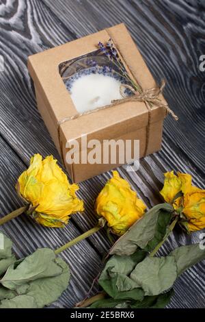 Bougie décorative dans un emballage artisanal. Noué avec un cordon et décoré de branches de lavande. Les roses séchées se trouvent à proximité. Banque D'Images