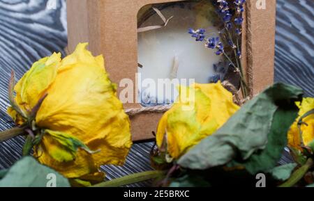 Bougie décorative dans un emballage artisanal. Noué avec un cordon et décoré de branches de lavande. Les roses séchées se trouvent à proximité. Banque D'Images