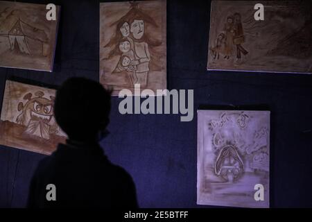 Killi, Syrie. 27 janvier 2021. Un enfant regarde des peintures lors d'une exposition organisée par l'équipe de bénévoles Violet dans un camp du village de Killi où tous les portraits sont peints de la boue pour attirer l'attention du monde sur les conditions des personnes déplacées pendant la saison d'hiver. Credit: Aras Alkharboutli/dpa/Alamy Live News Banque D'Images