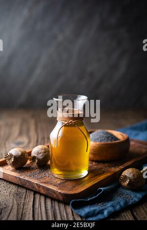 Huile de graines de pavot pressée à froid organique dans une carafe en verre sur fond en bois Banque D'Images