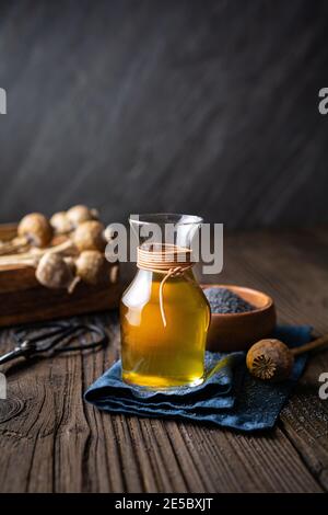 Huile de graines de pavot pressée à froid organique dans une carafe en verre sur fond en bois Banque D'Images