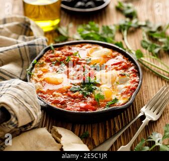 Plat traditionnel shakshuka servi dans une poêle en fonte sur une table en bois, vue rapprochée Banque D'Images