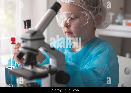 Petite fille d'une école primaire, utilisant la recherche au microscope, les tests en classe scientifique. Petite fille faisant de la recherche en biochimie en laboratoire. Photo de haute qualité Banque D'Images