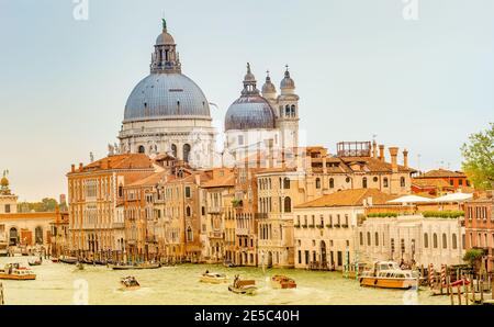 Vue colorée sur la basilique Santa Maria della Salute et le Grand Canal animé au coucher du soleil, Venise, Italie Banque D'Images