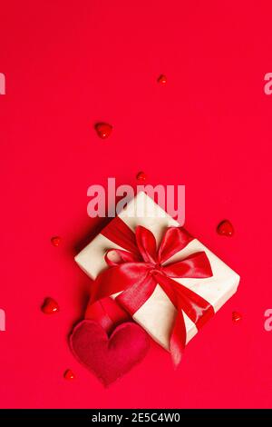 Fond de carte de voeux pour la Saint-Valentin avec boîtes-cadeaux, rubans rouges et coeurs assortis. Concept de mariage ou d'anniversaire, lieu pour le texte, pose à plat. Rouge mat Banque D'Images