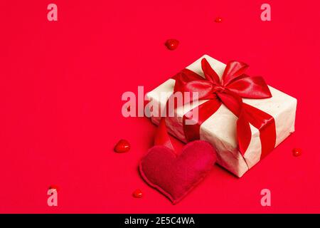 Fond de carte de voeux pour la Saint-Valentin avec boîtes-cadeaux, rubans rouges et coeurs assortis. Concept de mariage ou d'anniversaire, lieu pour le texte, pose à plat. Rouge mat Banque D'Images