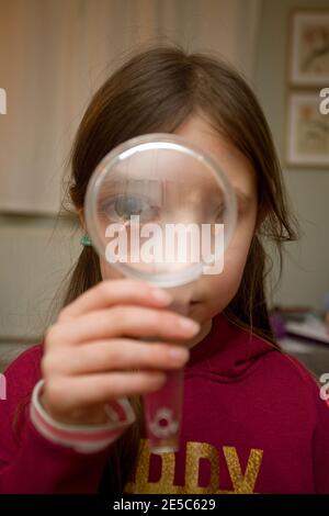 Jeune fille à la loupe à travers Banque D'Images