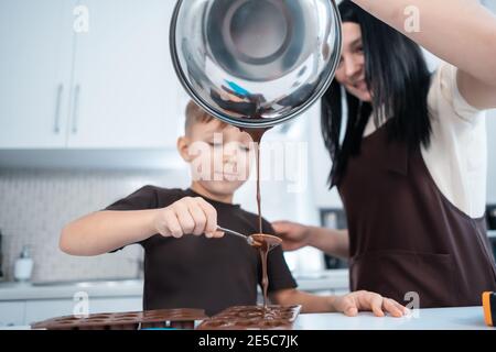 bonne mère et enfant de faire des bonbons au chocolat ou des bonbons à cuisine moderne Banque D'Images