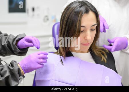 secrétaire médical préparant le traitement dentaire mettant sur le bavoir dentaire sur le patient. Photo de haute qualité Banque D'Images
