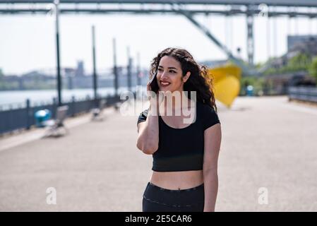 Jeune femme marchant et parlant au téléphone le long de la ville front de mer Banque D'Images