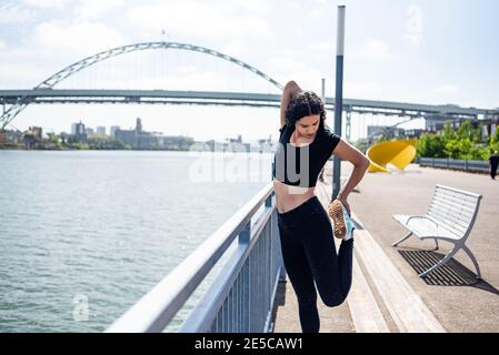 Femme qui s'étire sur le front de mer avec rivière et pont à l'intérieur arrière-plan Banque D'Images