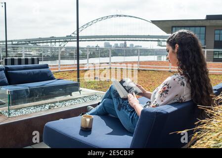 Femme lisant un livre sur le toit à l'extérieur avec le pont et ville Banque D'Images